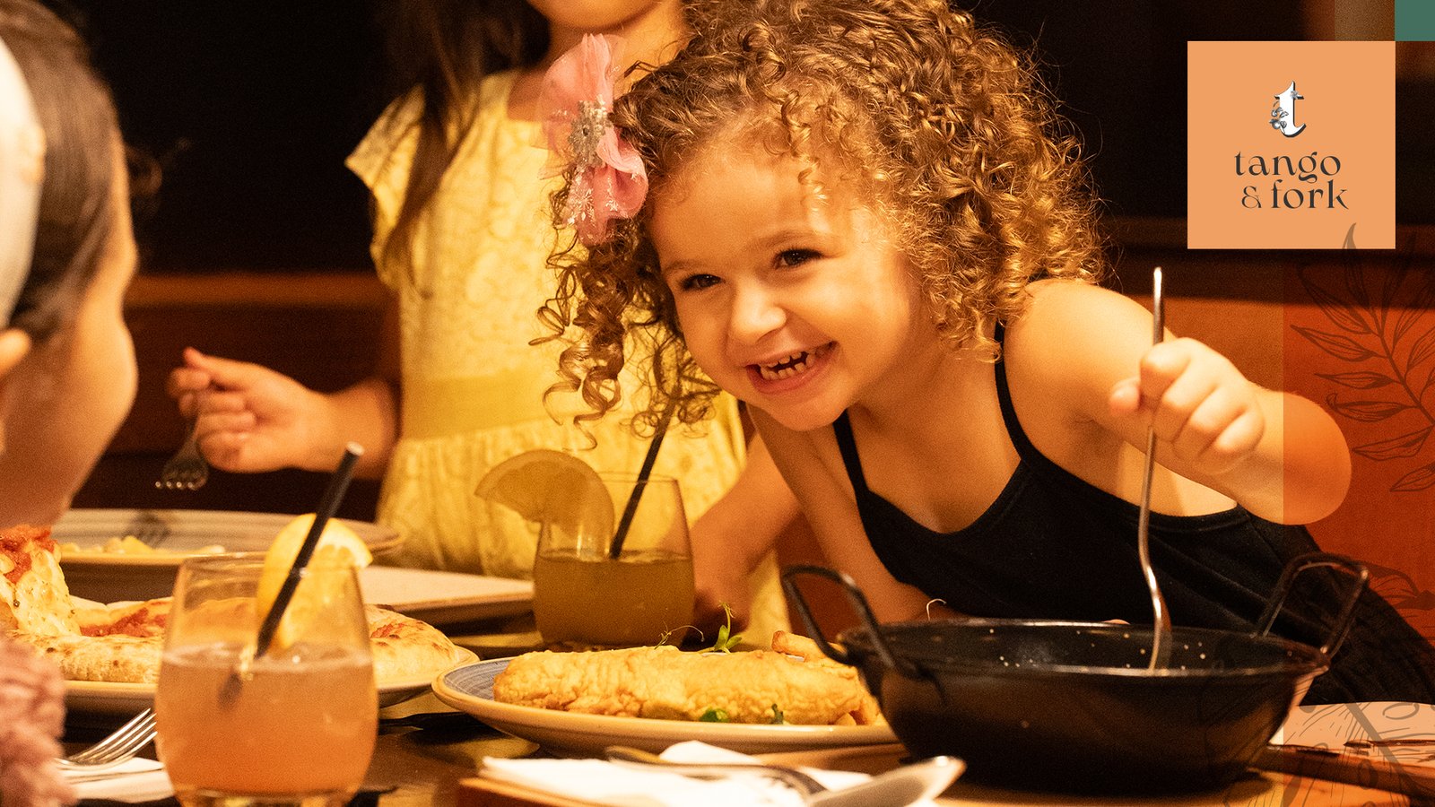 Young girl smiling while dining with other children at Tango and Fork restaurant.