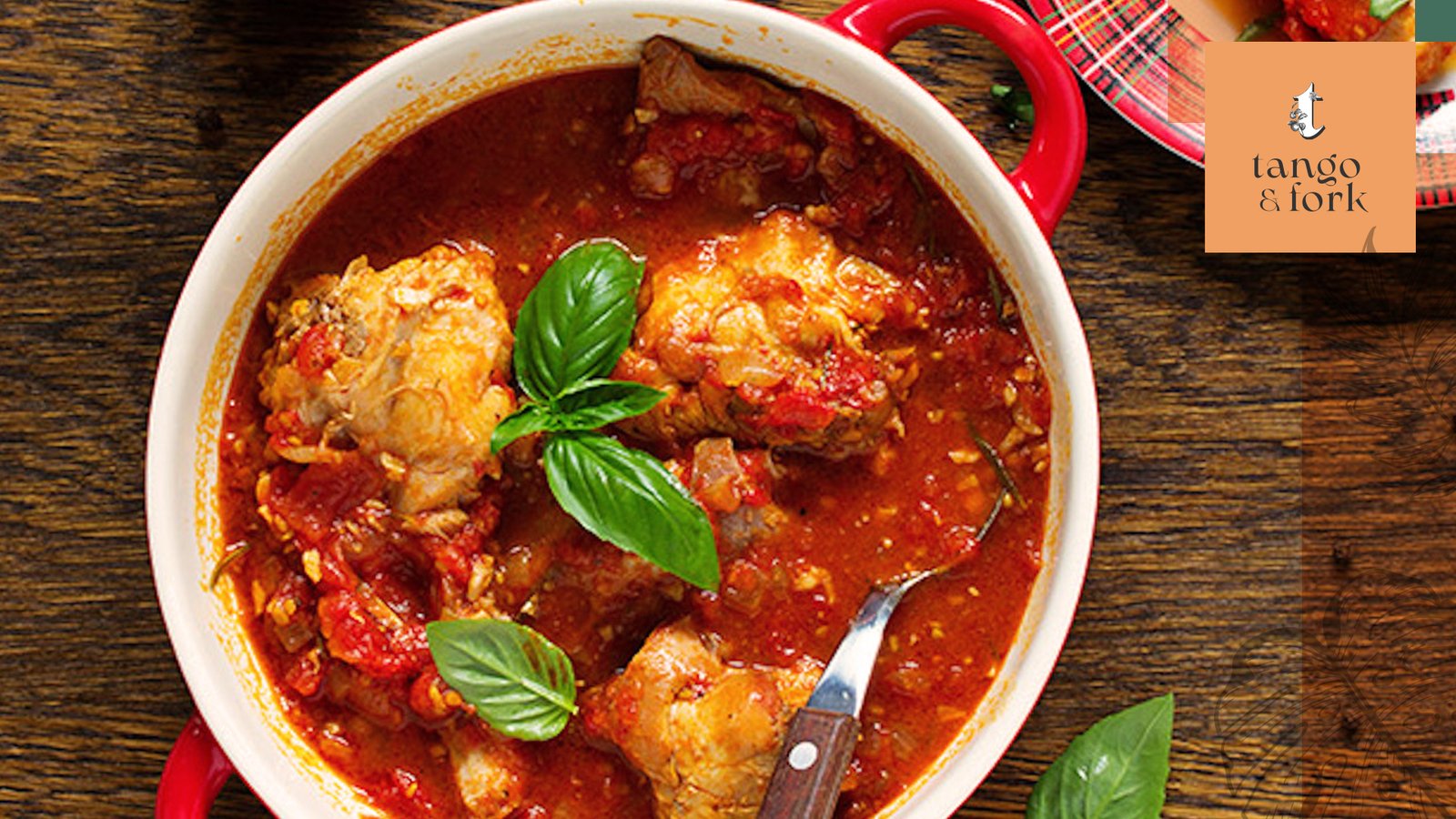 Hearty chicken stew in rich tomato sauce served in a red pot at Tango and Fork